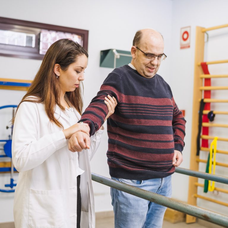 Physiotherapist assisting patient walking with disability during rehabilitation